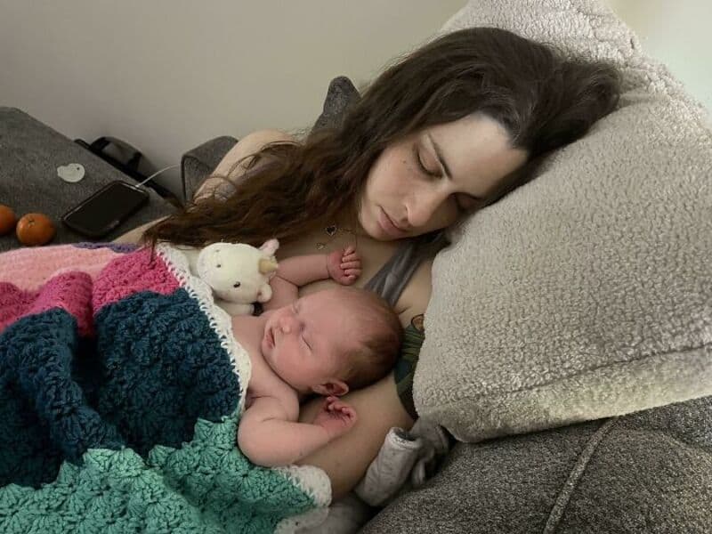Mother and infant resting together on a soft couch, showcasing maternal bonding and comfort.