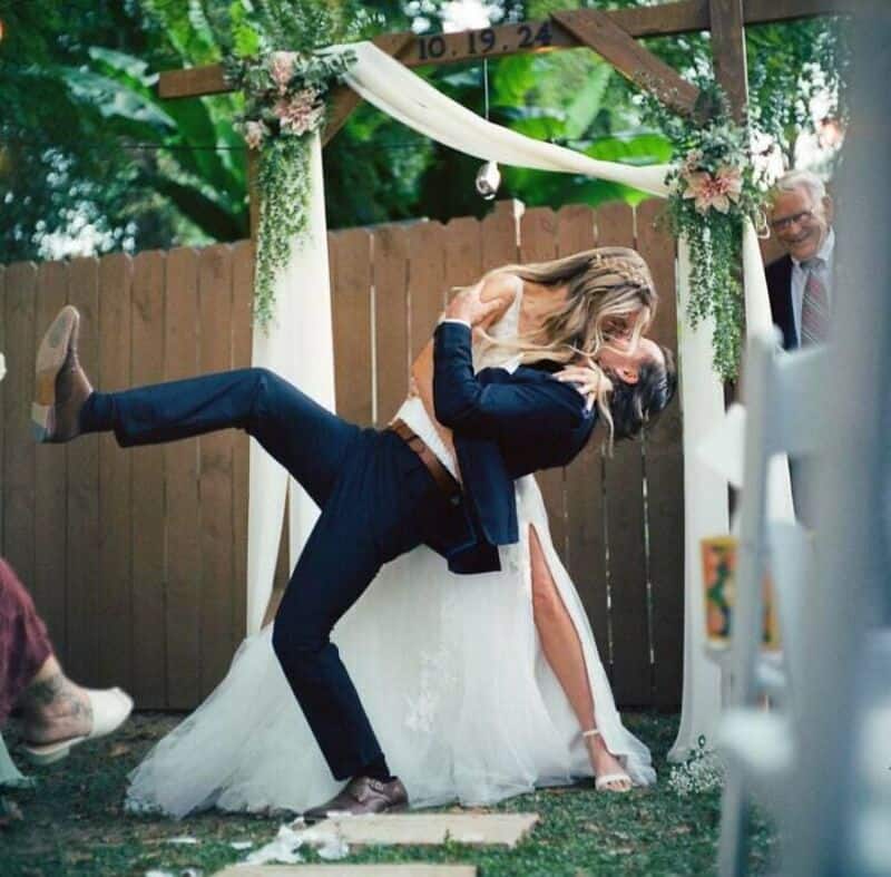 Vibrant wedding scene featuring a bride and groom dancing happily at an outdoor ceremony.