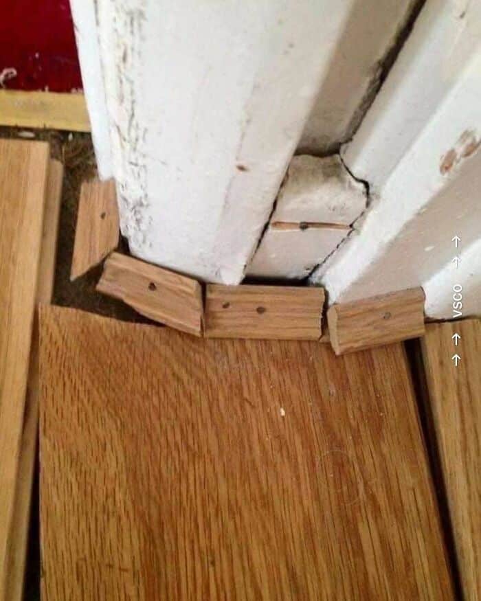 Broken baseboard and damaged wall corner with wood flooring.