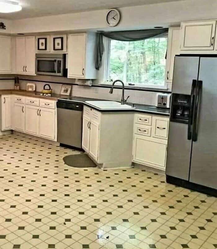 Kitchen with white cabinets, black countertops, and a large window.