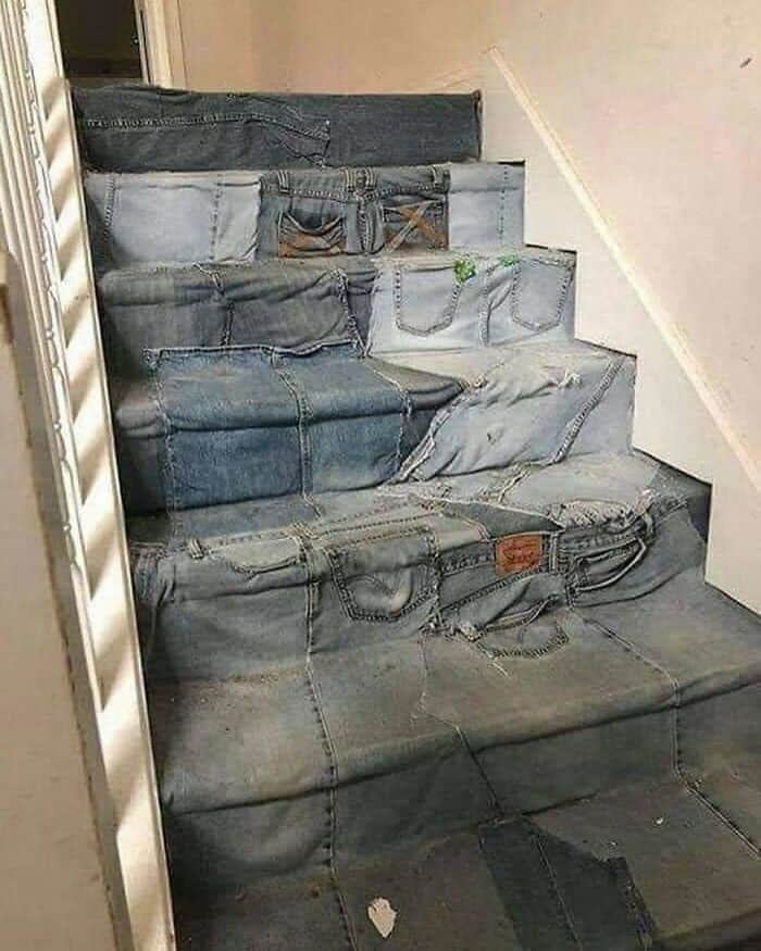 Stack of various denim jeans on stairs, different shades and styles.
