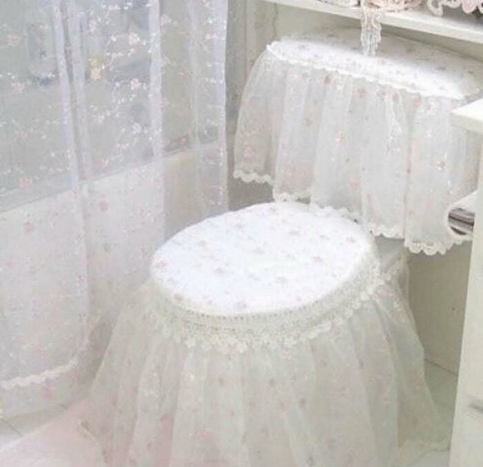 Vintage white lace-covered stool and side table with lace curtains in background.