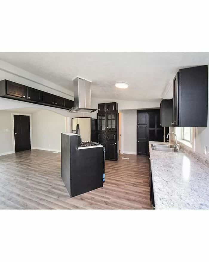 Modern kitchen with black cabinets and granite countertops.