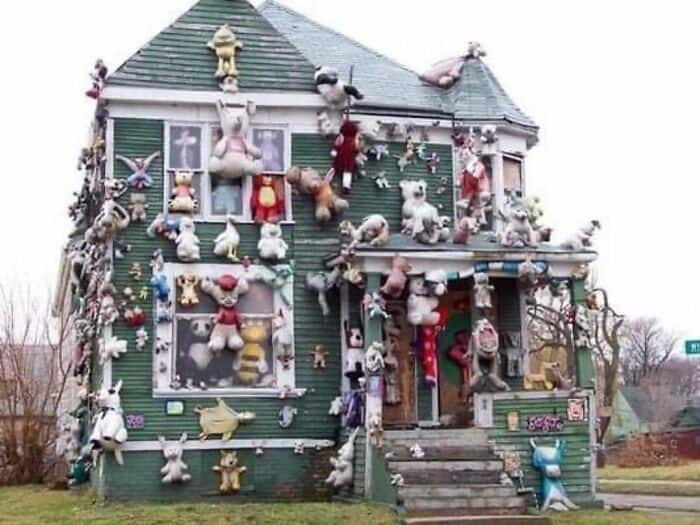 House decorated with numerous stuffed animals and plush toys hanging outside.