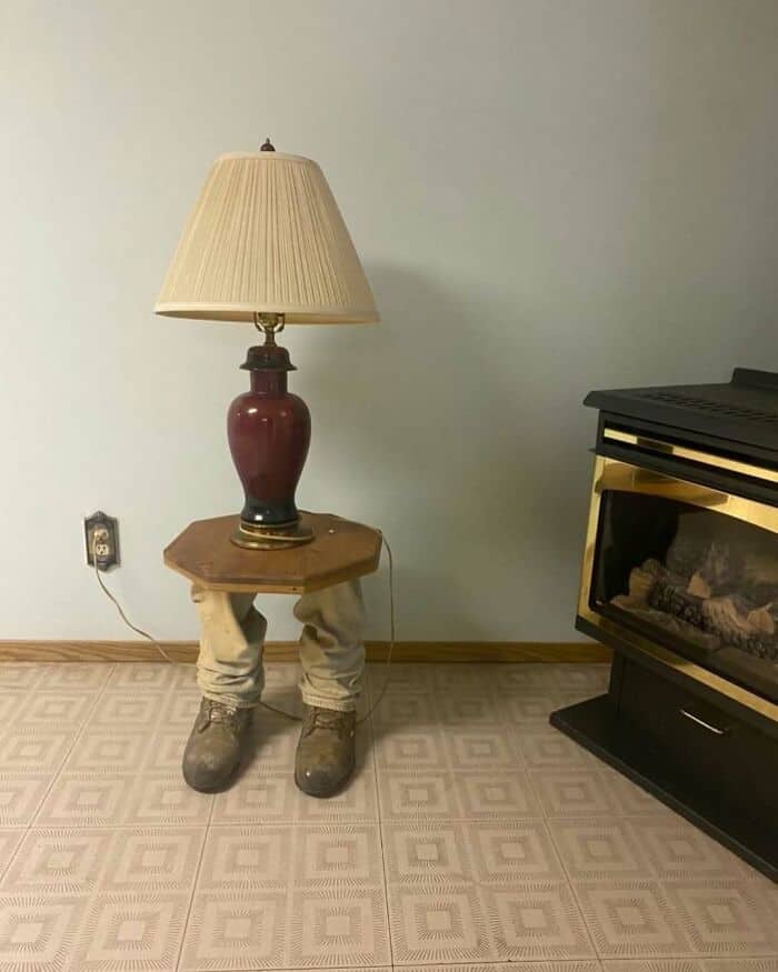 Unique lamp with a lampshade on a table with legs and boots.