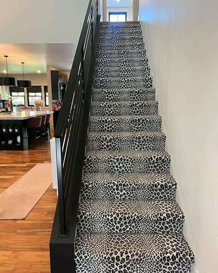 Leopard print staircase with black railing leading to upper floor.