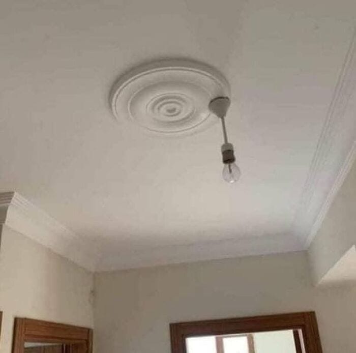 Broken light bulb hanging from ceiling with decorative ceiling medallion.