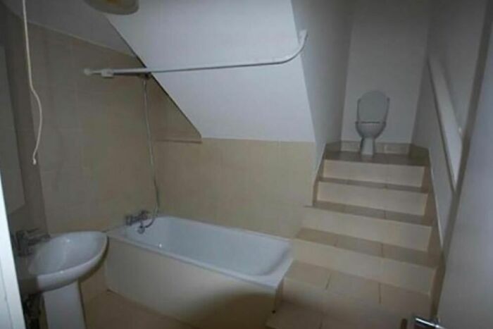 A bathroom with a bathtub, sink, and toilet on a raised platform with stairs.