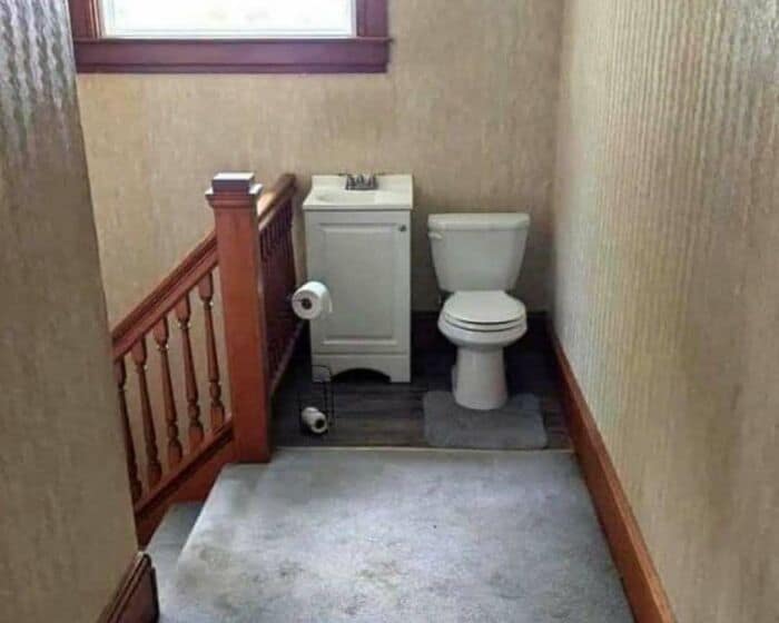Small bathroom with toilet, sink, and window, narrow space.