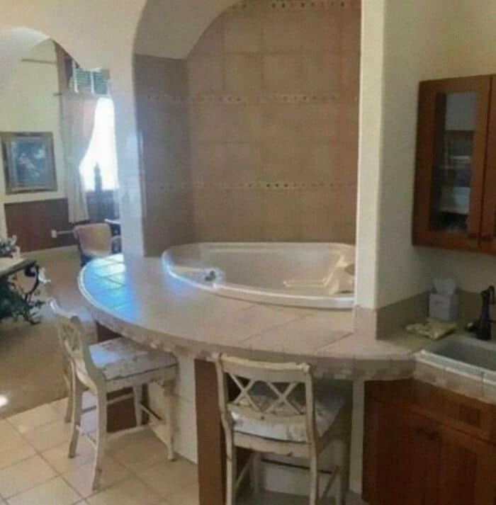 Hot tub in a cozy living space with seating area and kitchen in the background.