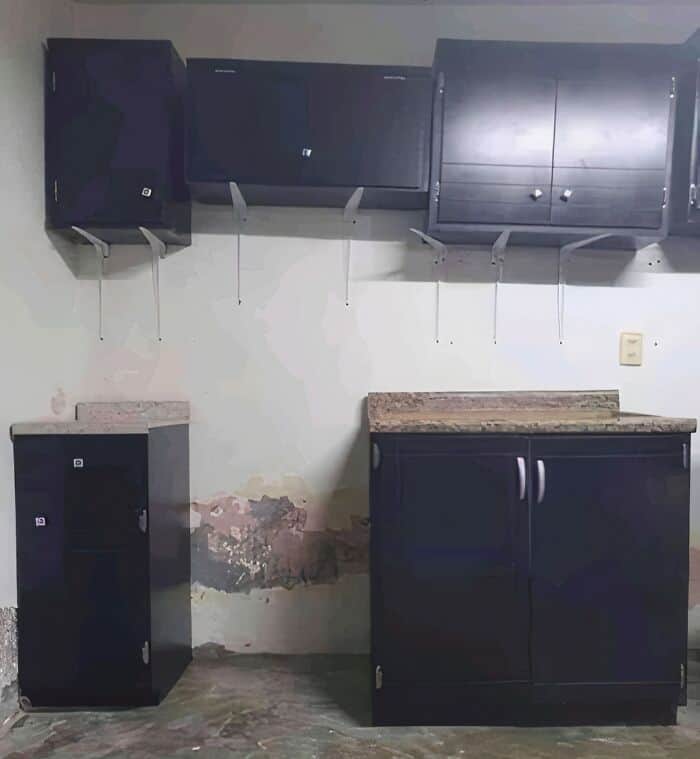 Unevenly mounted kitchen cabinets and damaged wall in a home improvement fail.