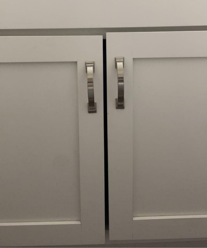 Door handles misaligned on kitchen cabinets, causing uneven gaps and a flawed appearance.