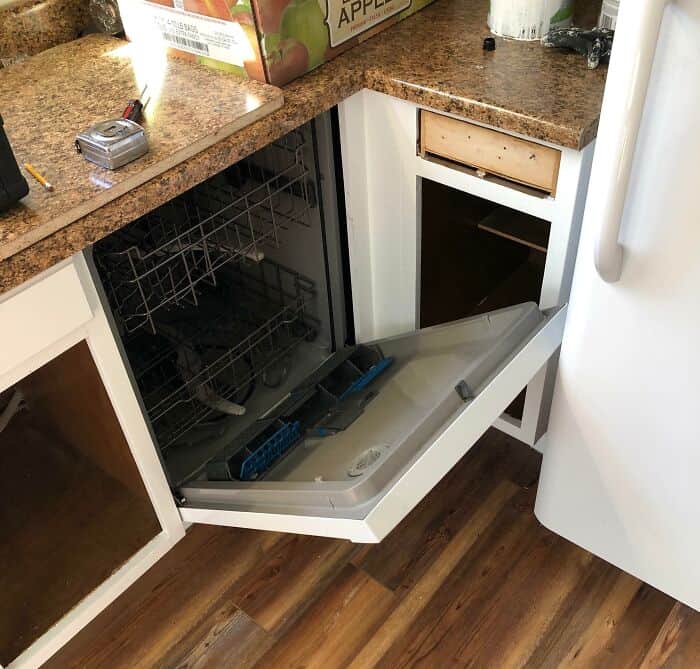 Broken dishwasher door installation in a kitchen cabinet.