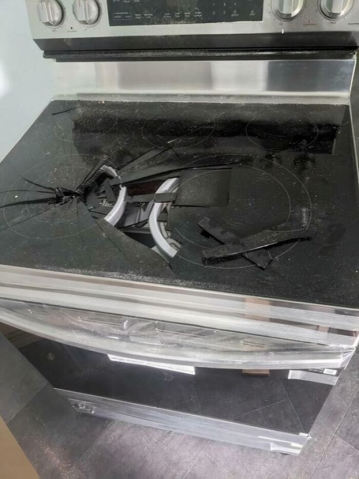 Damaged glass stove with broken burners and shattered surface.