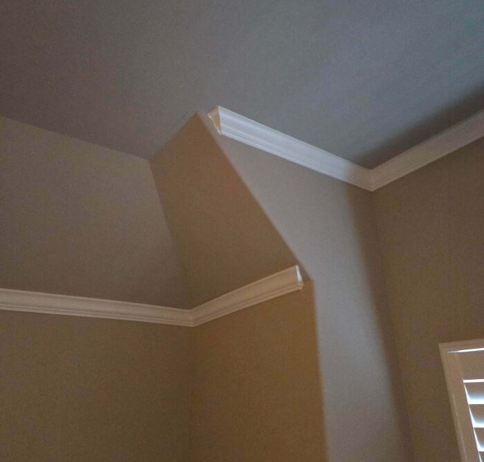 Ceiling corner showing poorly installed crown molding with uneven paint and gaps, highlighting a hom.