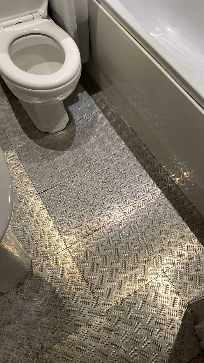 Cracked bathroom floor with uneven tiles and visible damage.