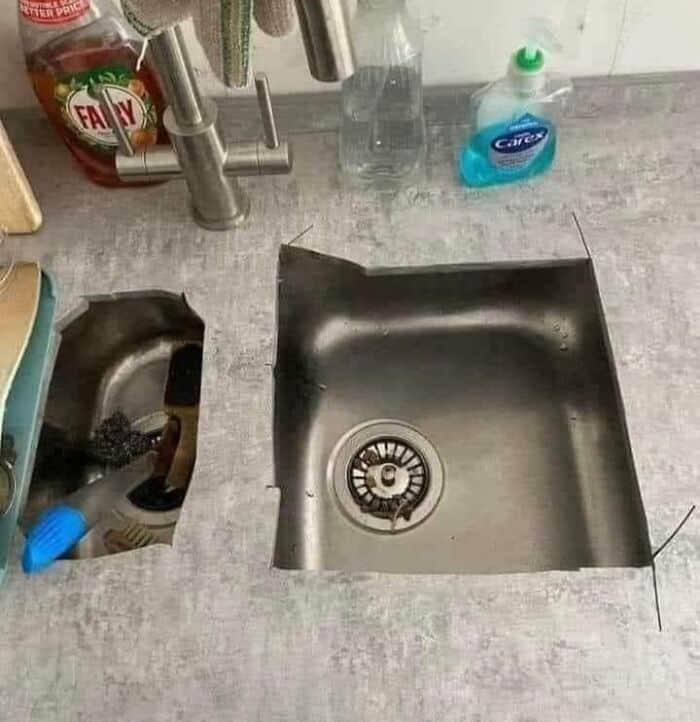 Improperly installed kitchen sink with missing drain cover and countertop gap.