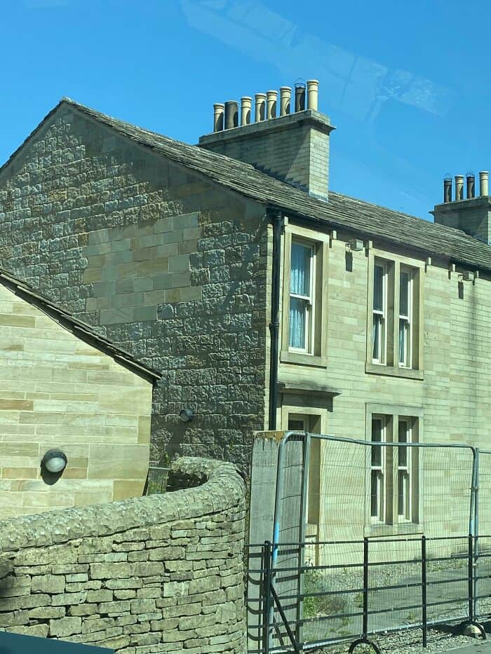 Charming stone house with chimneys and stone wall, showcasing traditional architecture.