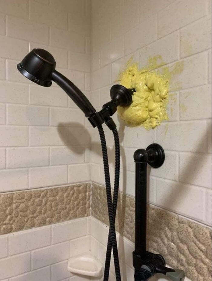 Showerhead mounted incorrectly with yellow insulation foam around the pipe.