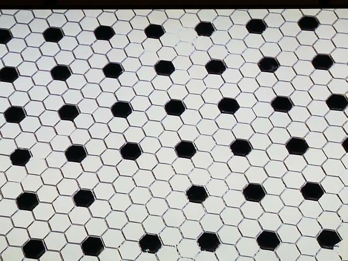 Hexagonal tile floor with black tiles and white grout, illustrating a poor installation or design mi.