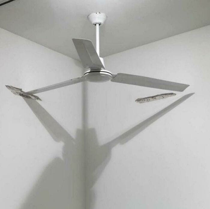 Broken ceiling fan blades with uneven shadows on the wall.