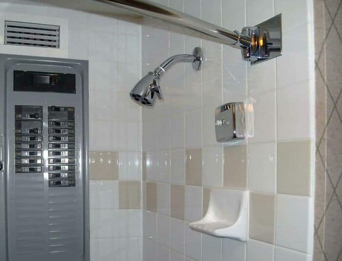 Shower head installed incorrectly, pointing at the wall in a bathroom.