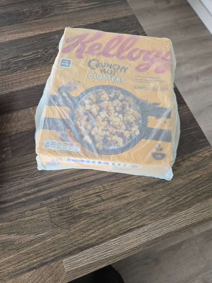 Kellogg's Crunchy Nut Clusters cereal box on wooden table surface.