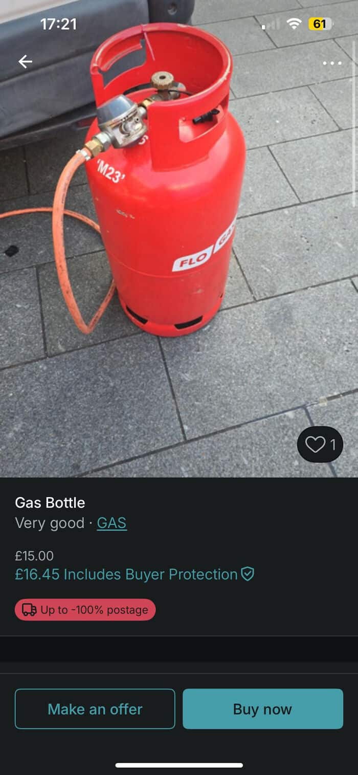 Red gas cylinder on tiled floor with hose and valve.