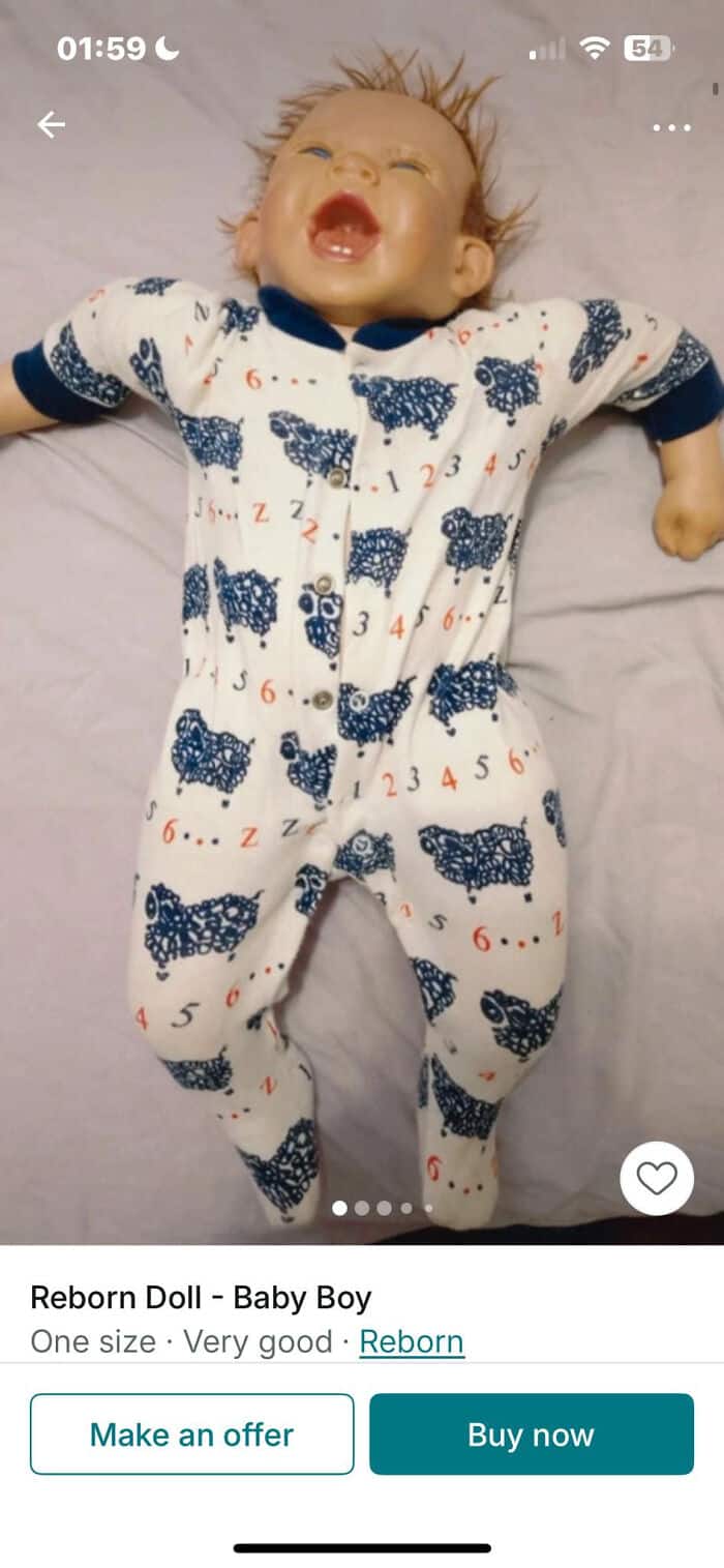 Reborn baby doll wearing adorable blue and white pajamas with animal patterns, lying on a soft surfa.