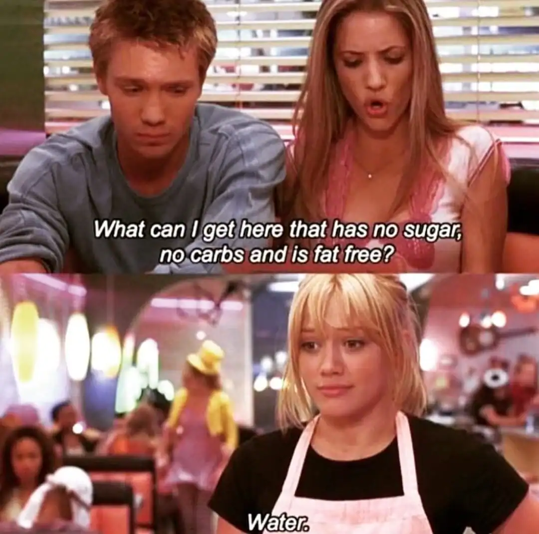 Young women discussing sugar-free food options at a cafe, with a waitress serving drinks in the back.