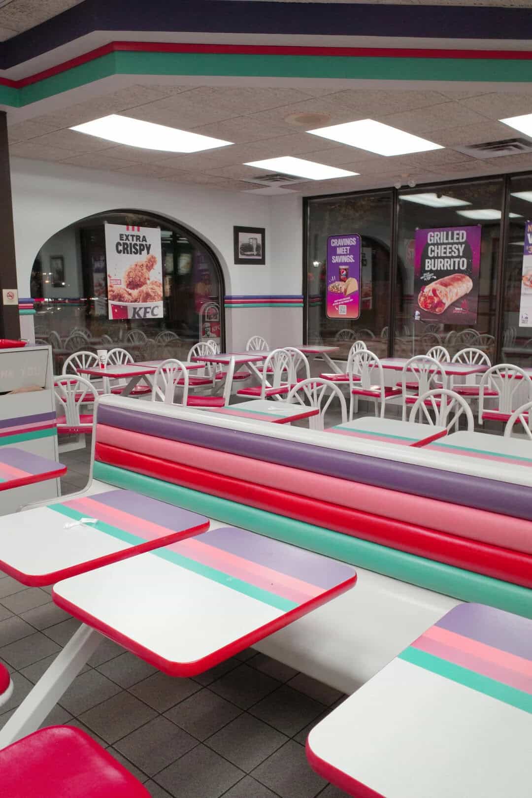 Bright, colorful retro diner interior featuring pink, mint, and white tables with matching chairs, l.