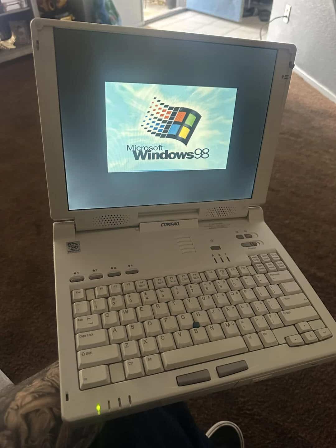 Vintage Windows 98 laptop with open screen displaying the Windows logo.