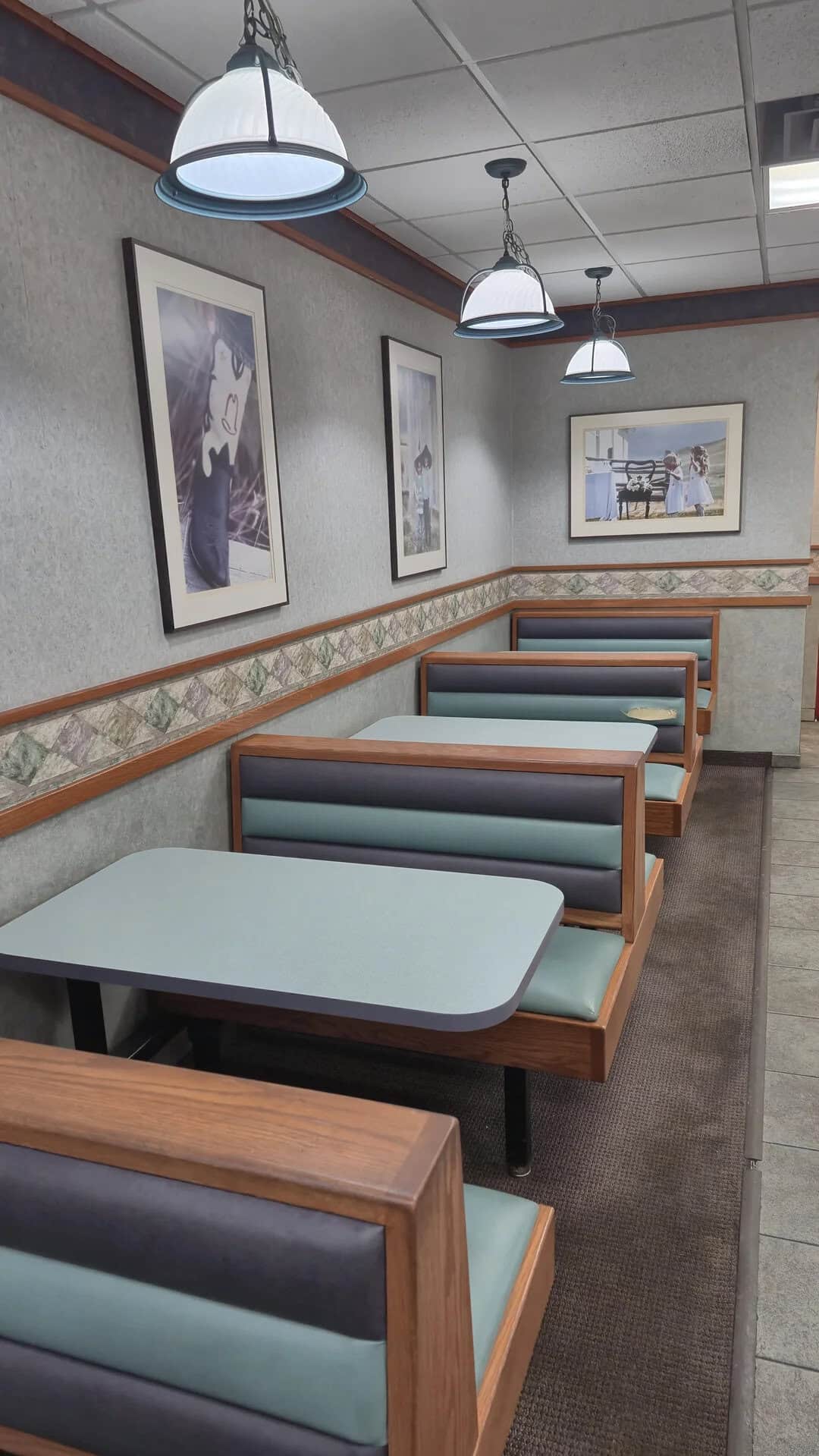 Comfortable booth seating in a casual restaurant setting with framed artwork and pendant lighting.