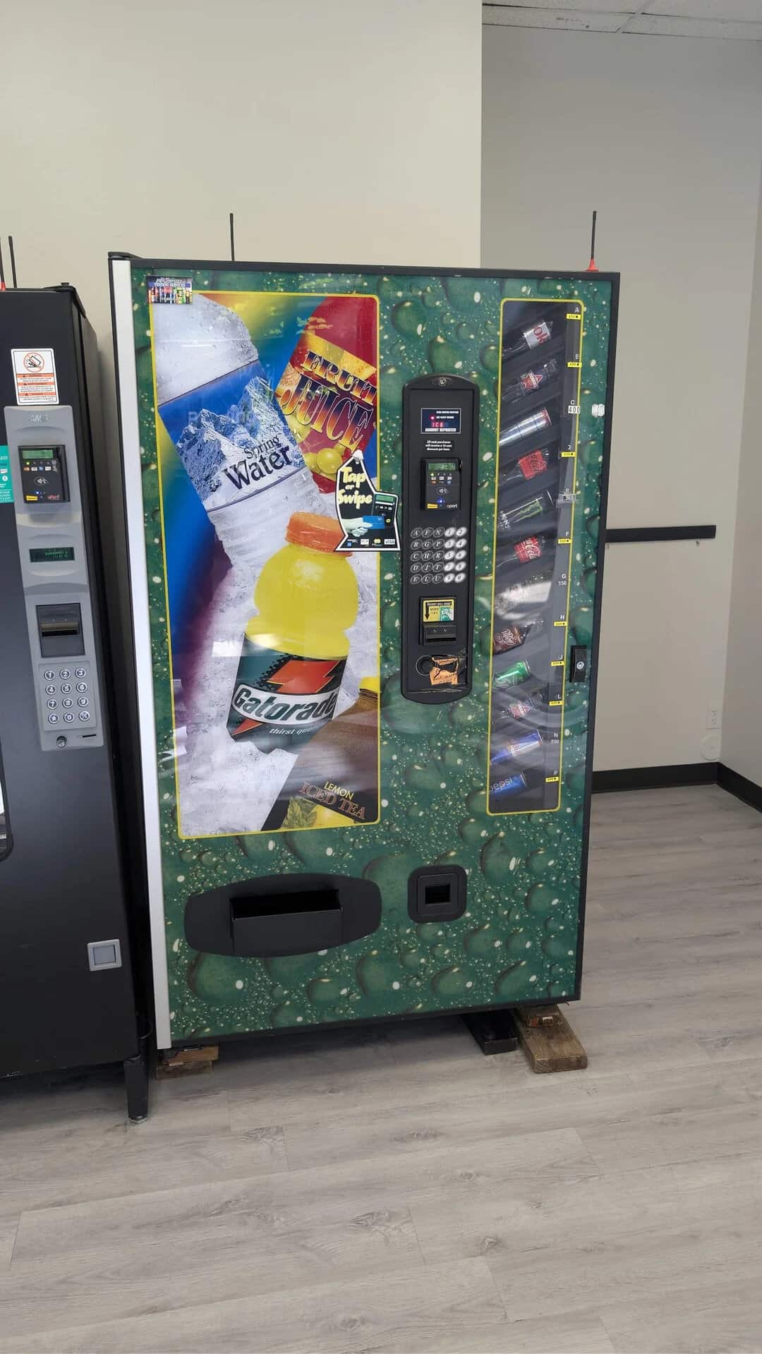 Vending machine offering snacks and beverages, including water, soda, and chips, in a modern setting.