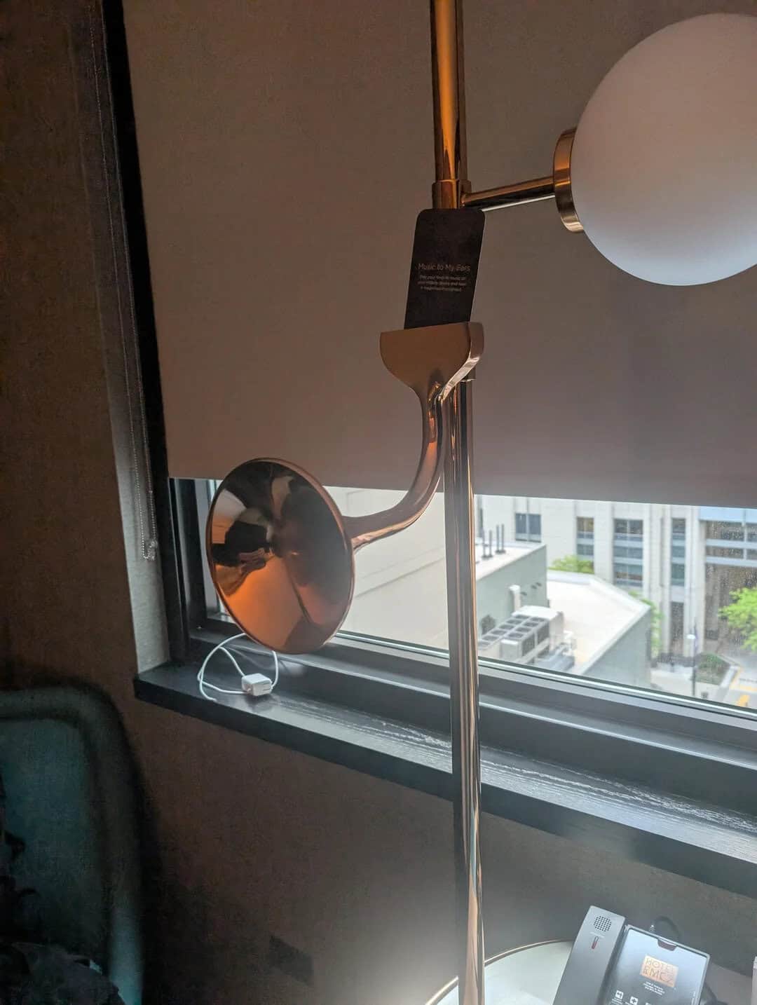 Wall-mounted lamp with spherical shade and metallic arm in a modern interior setting.
