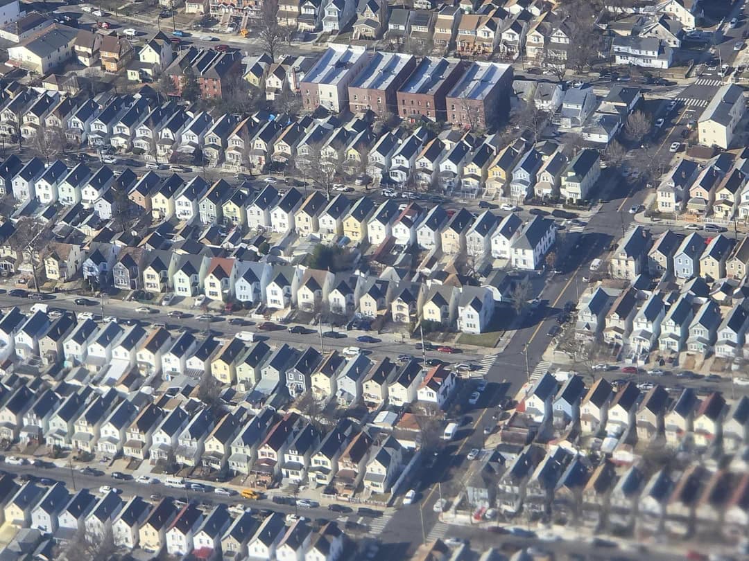 Aerial view of a densely packed suburban neighborhood with rows of houses and streets.