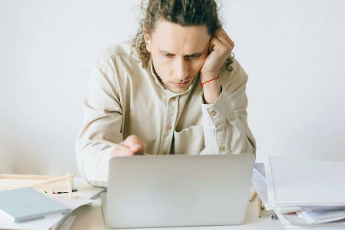 Man focused on laptop, studying or working at desk.