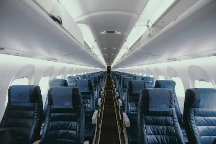Airplane interior with blue seats and overhead storage, ready for passengers.