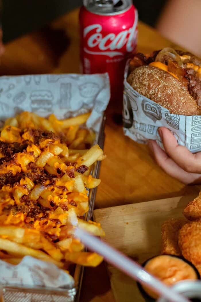 Cheeseburger, fries, and soda on a wooden table, casual fast food meal.