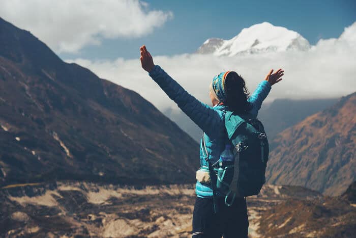 Woman with backpack enjoying scenic mountain landscape with snow-capped peaks.