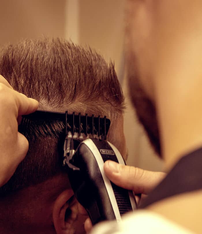 Men's haircut grooming with electric clippers at barbershop.