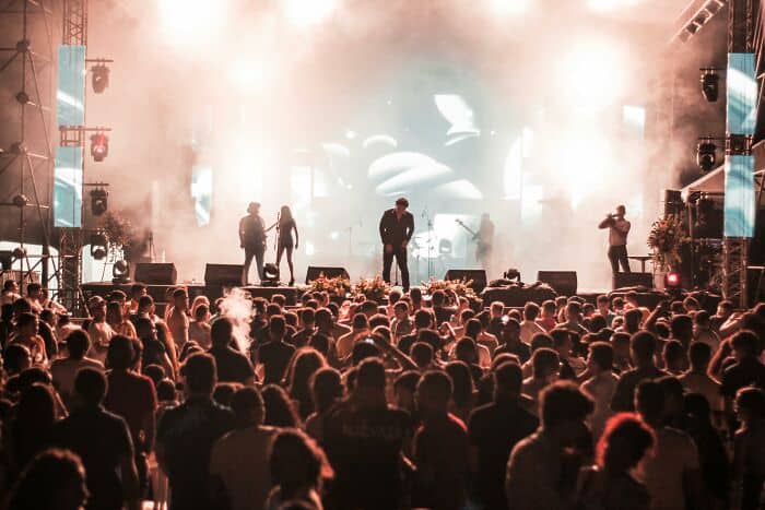 Live concert scene with a crowd and performers on stage under bright lights.