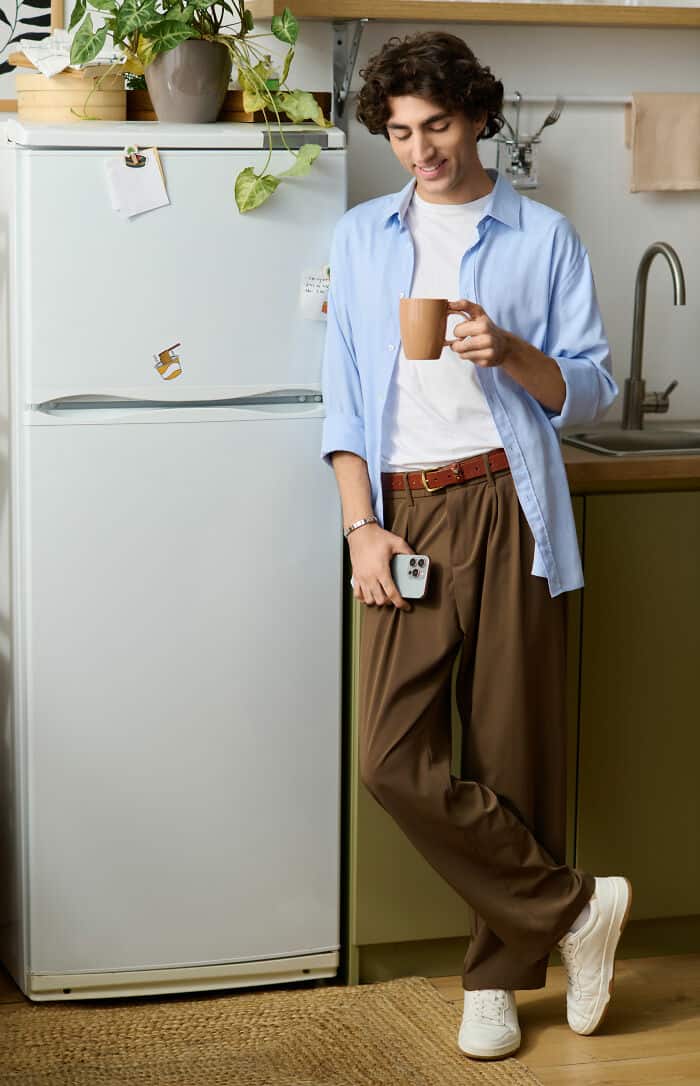 Young man holding coffee mug in modern kitchen setting.