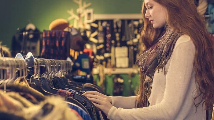Woman browsing clothing racks in a boutique store, selecting fashionable apparel.