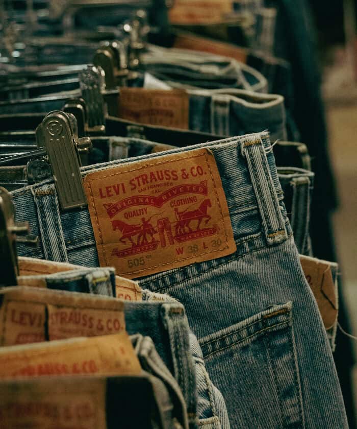 Classic Levi's denim jeans with leather patch on waistband, hanging on display rack.