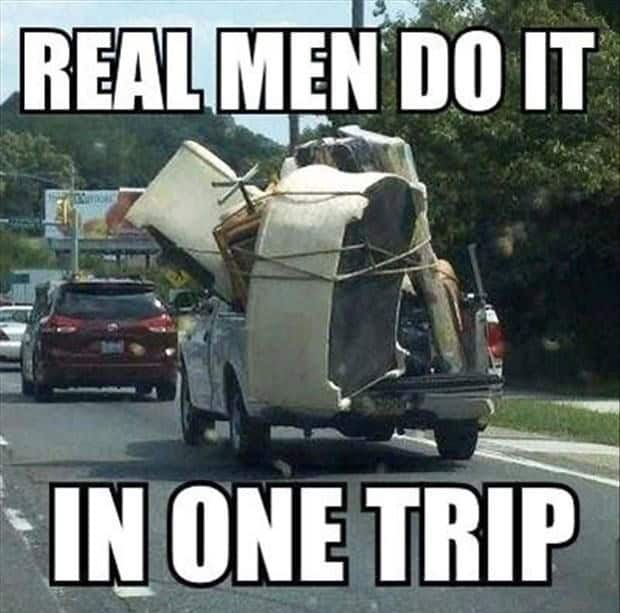 Overloaded pickup truck carrying furniture and household items on a busy road.