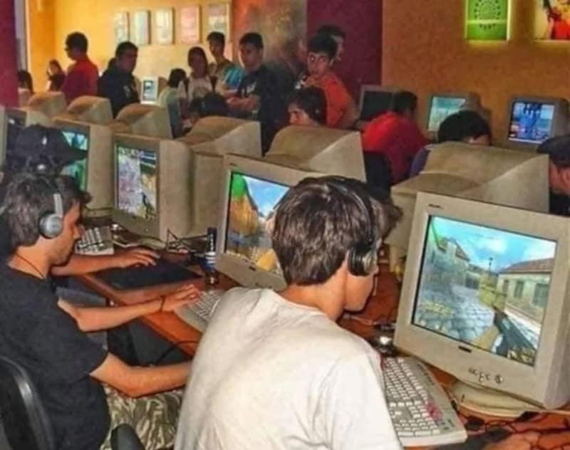 Kids gaming on desktop computers in a gaming center with colorful decor.