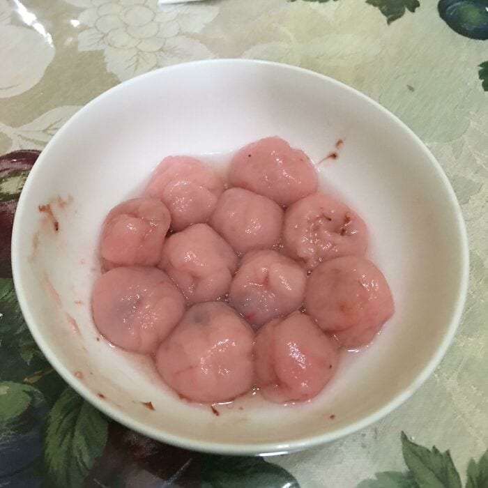 Unusual pink food balls in a white bowl, looking slimy and unsettling, fitting the "cursed food" the.