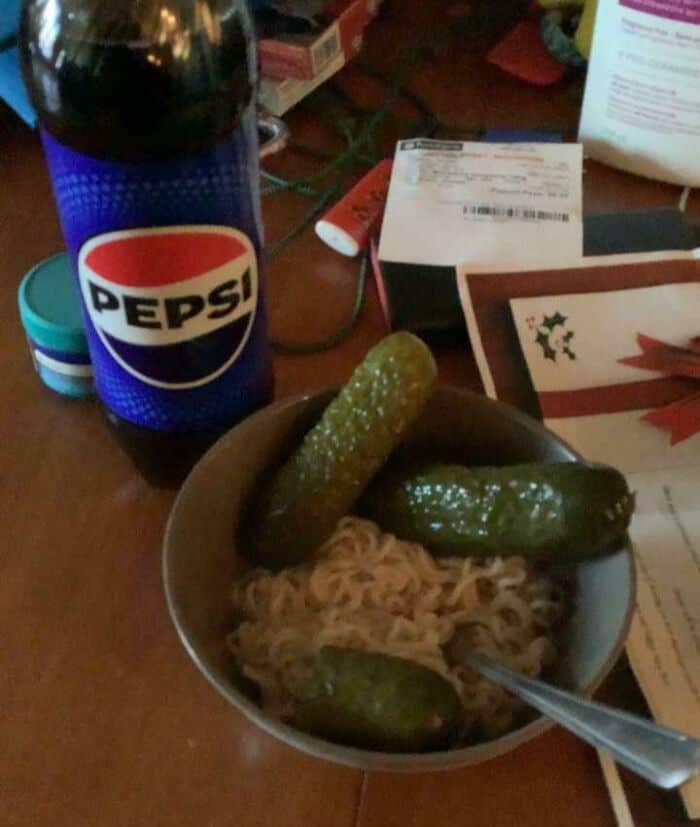 Unappetizing bowl of noodles with four pickles and a Pepsi bottle.