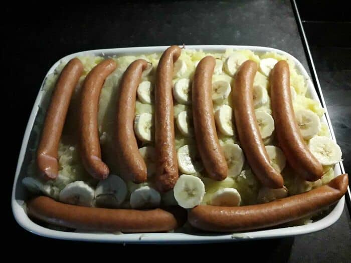 Unusual food arrangement with sausages and banana slices on a tray.